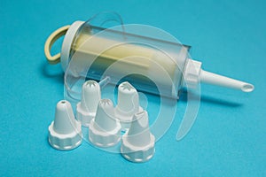 Cream injector cooking bag and set of cream piping nozzles on blue background
