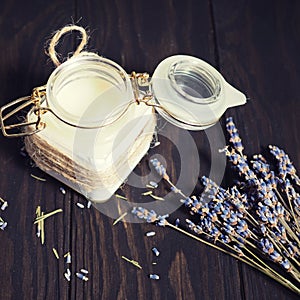 Cream in a jar and dry lavender on a wooden background