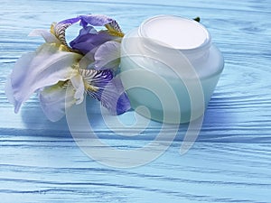 Cream moisturizer cosmetic aromatic organic health ointment iris flower on a blue wooden background