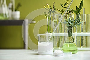 Cream and natural ingredients on white table in cosmetic laboratory