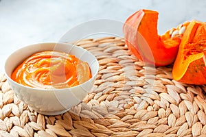 Cream is poured into a bowl of orange pumpkin puree soup. Autumn comfort food concept