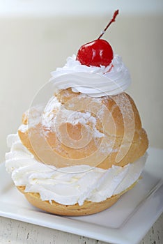 Cream puff filled with whipped cream and topped with a cherry