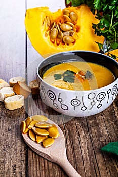 Cream pumpkin soup with fresh herbs and crackers on dark wooden background. Healthy food. Selective focus.