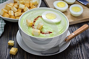 Cream soup with avocado, garnished with egg and croutons.