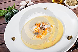 Cream soup with chicken breast, mushrooms, herbs on plate on dark wooden background.