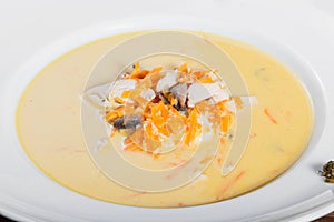 Cream soup with chicken breast, mushrooms, herbs on plate on dark wooden background.