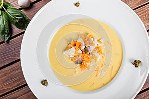 Cream soup with chicken breast, mushrooms, herbs on plate on dark wooden background