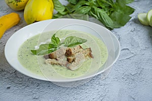 Cream soup made from mashed potatoes with zucchini and basil and crackers on a light background. Space for text