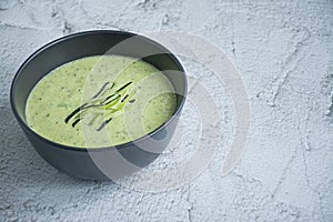 Cream soup made from mashed potatoes with zucchini and basil and crackers on a light background. Space for text