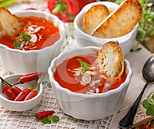 Cream soup of roasted pepper  with the addition of almond flakes, chili peppers, fresh herbs and toasts in a white ceramic bowl, c