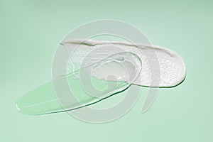 Cream texture. cosmetic cream stroke, face care gel. White cream ant transparent gel smear on green background. Facial