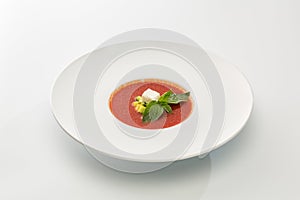 Cream of tomato soup with cheese and basil in a plate isolated o