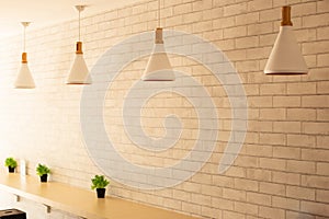 Cream wall bar interior with a wooden bar and four white of lamps