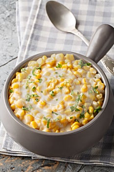 Creamed Corn is a classic side dish consists of tender corn kernels bathed in a rich creamy sauce closeup on the bowl. Vertical