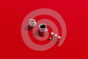 Creamer, cup of espresso and sugar with golden spoon on red