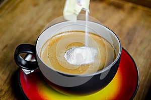 Creamer in to a cup of coffee.
