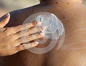Creaming the back of a boy on the beach