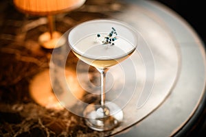 Creamy alcoholic cocktail in the glass decorated with a dried flower on the table