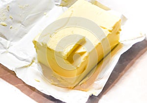 Creamy butter in its unwrapped foil paper. Isolated on light table