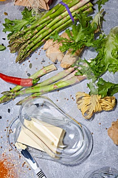 Creamy butter and a steel knife. Vegetables and greens on a table background. Hot chilies for a spicy homemade meal.