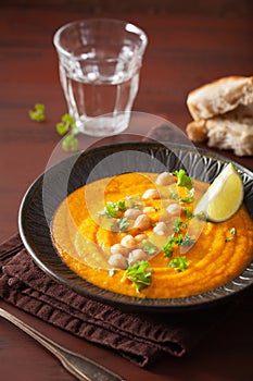 Creamy carrot chickpea soup on dark rustic background