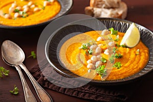 Creamy carrot chickpea soup on dark rustic background