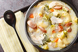 Creamy Chicken Sopas is a Filipino soup with pasta, vegetables, sausages and chicken close-up in a bowl. Horizontal top view photo