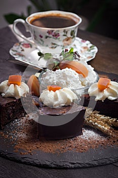 Creamy chocolate cake with apricot jam, whipped cream and cup of coffee