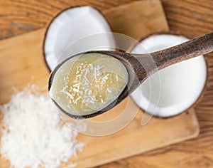 Creamy cocada, traditional brazilian coconut candy in a wooden spoon over unfocused background