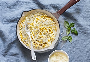 Creamy corn pasta in a cast iron skillet on a blue background