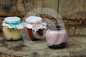 Creamy dessert in a small glass jars with ribbon on a wooden background