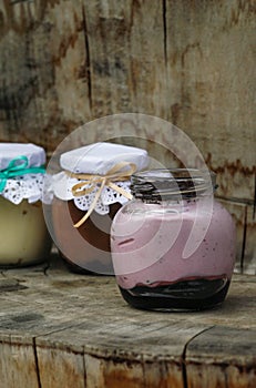 Creamy dessert in a small glass jars with ribbon on a wooden background