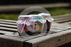 Creamy dessert in a small glass jars with ribbon on a wooden background