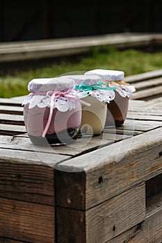 Creamy dessert in a small glass jars with ribbon on a wooden background