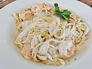 Creamy Italian Fettuccine Carbonara with prawns and bacon served on white dish for lunch