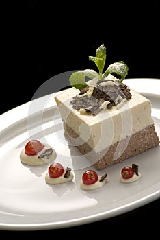 Creamy jelly mousse, pannacotta on a white porcelain plate, decorated with mint and red currant