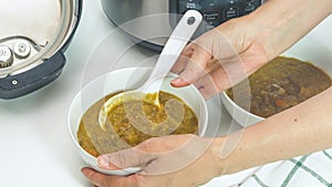 Creamy lentil soup cooked in multi cooker close up in a bowl, woman hands