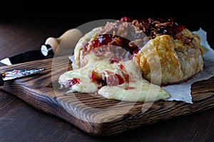 Creamy melted brie topped with cranberry sauce and bacon, pouring out of a pastry wrap