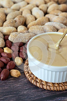 Creamy peanut butter in a bowl with golden spoon on wooden table
