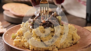 Creamy polenta with porcini mushrooms, bacon, served on a dark wooden background with a glass of red wine. Typical food