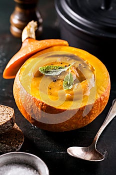 Creamy pumpkin soup puree in the whole squash on table ready to