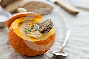 Creamy pumpkin soup puree in the whole squash on table ready to