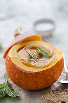 Creamy pumpkin soup puree in the whole squash on table ready to