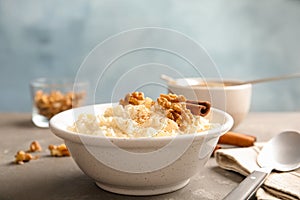 Creamy rice pudding with cinnamon and walnuts in bowl served on table.