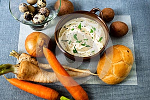 Creamy soup and raw vegetable on table