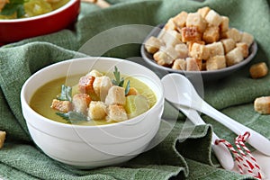 Creamy sweet potato soup with croutons and parsley in white bowl