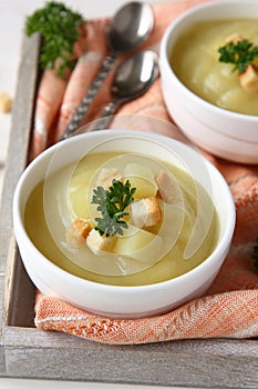 Creamy sweet potato soup with croutons and parsley in white bowl