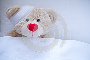 Creamy teddy bear injured in a wound after an accident
