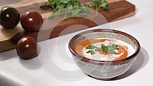 Creamy tomato soup with whipping cream and fresh parsley in a bowl