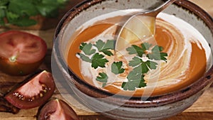 Creamy tomato soup with whipping cream and fresh parsley in a bowl
